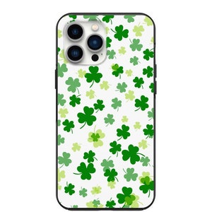 May include: A white phone case with a black border and a pattern of green four-leaf clovers.