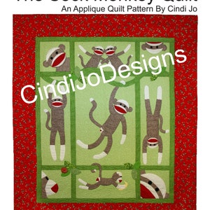 Peut inclure: Un modèle de courtepointe vert et rouge avec un motif d'applique de singe en chaussette. Le modèle comprend des instructions pour la réalisation d'une courtepointe de 183 cm x 213 cm, de courtepointes pour bébés, de tentures murales et de vrais singes en chaussette.