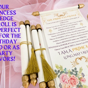 May include: A white scroll with gold accents and a tassel. The scroll is decorated with pink roses and green leaves. The text on the scroll reads "The Princess Pledge" and includes a list of qualities a princess should possess. The scroll is rolled up and tied with a gold ribbon.