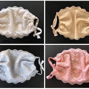 May include: Four lace face masks in different colors: white, beige, light blue, and pink. Each mask has a scalloped edge and ties.
