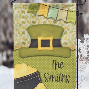 May include: A green leprechaun hat with a gold buckle and a pot of gold with the text "The Smiths" on a green and yellow garden flag.