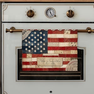 May include: A kitchen towel with a patchwork design of the American flag, with red and white stripes and a blue field of stars. The towel includes the text "The Smiths Est. 1995".