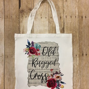 May include: White canvas tote bag with a floral design and the text "The Old Rugged Cross" and "Old Rugged Cross" printed on it.