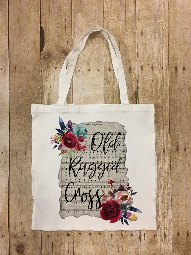 May include: White canvas tote bag with a floral design and the text "The Old Rugged Cross" and "Old Rugged Cross" printed on it.