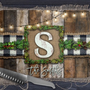 May include: A wooden chopping board with a burlap background and a black and white checked ribbon. The board has a rustic look and features a large letter "S" in a white font on a burlap background. The text "The Smiths" is written in a light blue font on the bottom of the board.