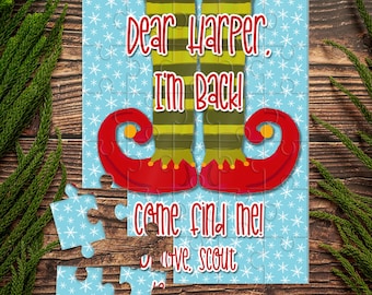 May include: A blue jigsaw piece with a snowflake pattern. The jigsaw piece features an elf's legs with red and green striped trousers and red shoes with pointy toes. The text on the jigsaw piece reads "Dear Harper, I'm back! Come find me! Love, Scout."