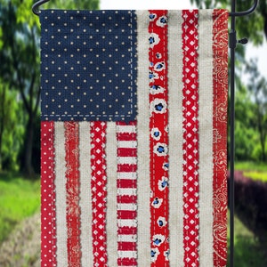 May include: A red, white, and blue American flag garden flag with a patchwork design. The flag is made of fabric with different patterns and textures, including polka dots, stripes, and floral designs.