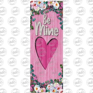 May include: Pink wooden sign with a heart-shaped cutout and the words "Be Mine" in white burlap letters. The sign is decorated with floral accents and greenery.