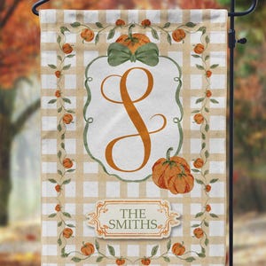 May include: A fall-themed garden flag with a beige and white checkered background. The flag features a large orange letter "S" inside a green-bordered frame. The top has a green bow and pumpkins. The bottom reads "THE SMITHS".