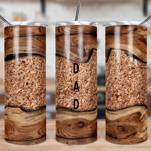 May include: Three stainless steel tumblers with a wood grain design. The middle tumbler has the word "DAD" printed on it.