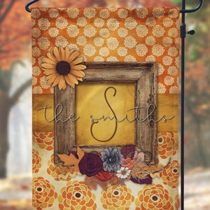 May include: A fall-themed garden flag with a rustic wooden frame and floral accents. The frame features the letter "S" and the text "the Smiths". The background is a pattern of orange and white flowers.