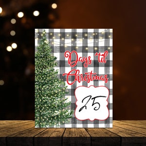 May include: A black and white buffalo plaid countdown sign with a Christmas tree and string lights. The sign says "Days 'til Christmas" and has a white circle with the number "25" in black.