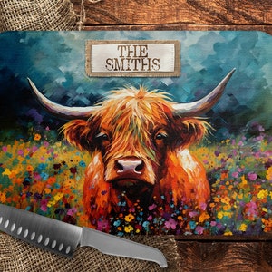 May include: A colorful cutting board with a painting of a Highland cow in a field of wildflowers. The text "THE SMITHS" is printed on a brown label at the top of the board.