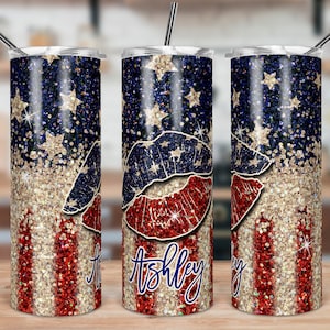 May include: Three stainless steel tumblers with a glitter design. The tumblers feature a red, white, and blue American flag design with a glitter overlay. The middle tumbler has the name "Ashley" written on it in a blue script font.