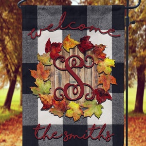 May include: A black and white checkered welcome garden flag with a fall leaf wreath and the letter "S" in the center. The text "Welcome the Smiths" is written in red cursive.
