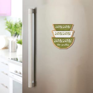 Puede incluir: Tres imanes de madera con forma de cuenco con un diseño floral verde y blanco están apilados en un frigorífico. El imán inferior tiene el texto "the smiths" en una fuente de escritura. Los imanes son un artículo decorativo con temática de cocina.