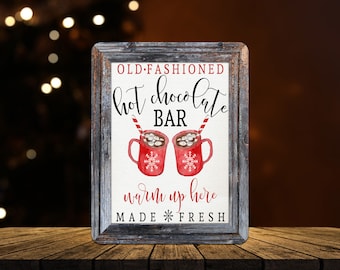 May include: A framed sign with a rustic, weathered wood frame. The sign reads "OLD FASHIONED Hot Chocolate BAR" with two red mugs of hot chocolate. The text "warm up here" and "MADE FRESH" are also included.