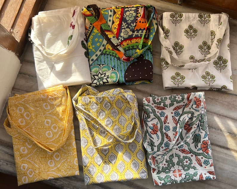 May include: Six tote bags with different patterns. The bags are made of white cotton fabric with colorful printed designs. The designs include floral patterns, geometric patterns, and abstract patterns.