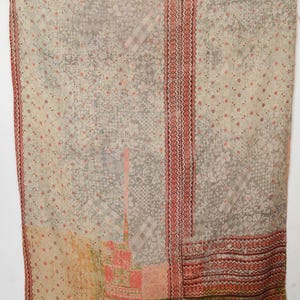 May include: A vintage textile with a patchwork design. The fabric features a mix of beige, grey, and red hues, with floral and geometric patterns. The edges are trimmed with a red border, creating a rustic and textured appearance.