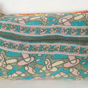 May include: A colorful patterned pillow with a turquoise, pink, and green design. The pillow is made of a woven fabric and has a rectangular shape.