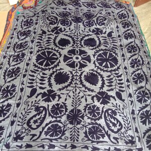 May include: A gray fabric throw blanket with a black floral embroidery design. The design features intricate floral patterns and paisley motifs.