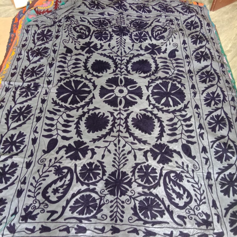 May include: A gray fabric throw blanket with a black floral embroidery design. The design features intricate floral patterns and paisley motifs.