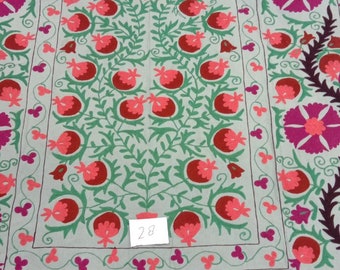 May include: A white cotton fabric with a hand-stitched embroidery design featuring a repeating pattern of red and pink pomegranates, green leaves, and purple flowers. The fabric has a number "28" written on it.