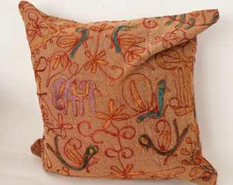 May include: A brown embroidered pillow with a floral and animal design. The pillow is decorated with colorful thread embroidery of flowers, leaves, and an elephant.