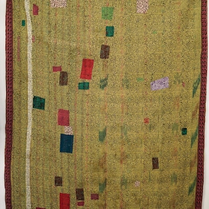 Puede incluir: Un edredón grande de color verde oliva con un estampado floral repetido y un borde burdeos. El edredón presenta varios parches cuadrados de colores en tonos de rojo, verde, azul y morado. Una franja vertical blanca recorre el lado izquierdo.