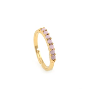 May include: A gold ring with a row of light pink stones.