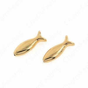 May include: Two gold-coloured fish charms. The charms are small and have a simple design.
