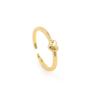 May include: A gold-coloured ring with a small heart-shaped design on the top.