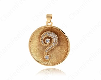 Könnte beinhalten: Ein runder Anhänger in Gold mit einem Fragezeichen aus klaren Strasssteinen. Der Anhänger hat eine gebürstete Oberfläche.