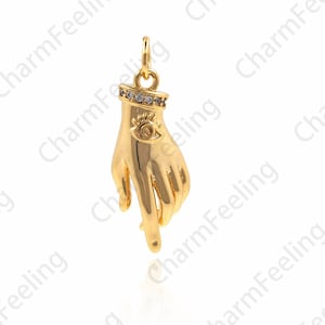 May include: Gold-toned pendant charm in the shape of a hand with an eye design on the palm. The eye is surrounded by small clear rhinestones.