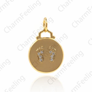 May include: A gold charm with a round pendant featuring two baby footprints outlined with small clear crystals.