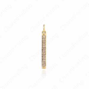 May include: A gold pendant charm with a vertical bar design, featuring a row of small clear cubic zirconia stones.