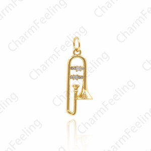 Peut inclure: Un charme trombone en or avec des accents de cristal transparent. Le charme est conçu pour être un pendentif pour un collier ou un bracelet.