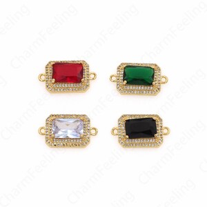 May include: Four gold-toned rectangular connector charms with different colored glass stones. The stones are red, green, clear, and black.