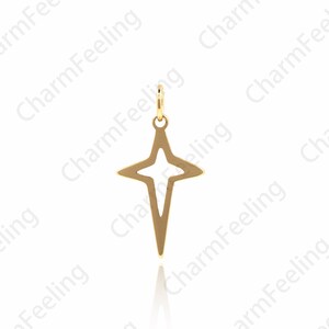 Puede incluir: Un colgante de estrella de color dorado con un centro hueco. La estrella tiene una punta puntiaguda y cuatro puntos.