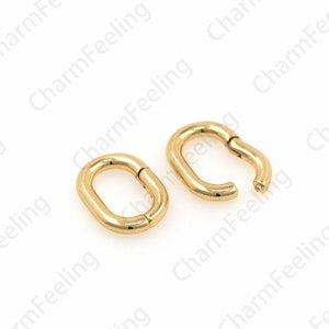 May include: Two gold-colored oval-shaped hoop earrings. One earring is closed, while the other is open, revealing a small clasp. The earrings have a smooth, polished finish and are set against a white background.