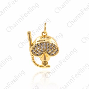 May include: A gold-toned pendant charm in the shape of a scuba diving mask with rhinestones. The mask has a clear plastic lens and a black snorkel.