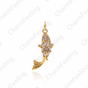 Puede incluir: Un colgante en forma de pez koi de tono dorado con piedras de circonita cúbica transparentes y rojas.