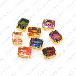 May include: Assortment of ten colorful, rectangular, faceted glass gems with gold settings. The gems are arranged in a scattered pattern on a white background.
