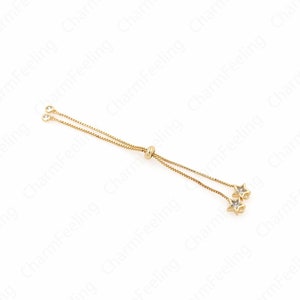 Peut inclure: Un bracelet en chaîne dorée avec un fermoir coulissant et deux breloques en forme d'étoile avec des cristaux transparents.