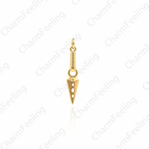 May include: A gold-colored metal charm shaped like a throwing knife. The charm has a pointed tip and a textured handle.
