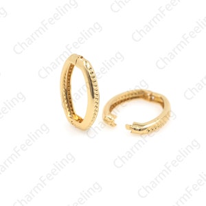 May include: Two gold-toned hoop earrings with a textured surface. The earrings are open and ready to be worn.