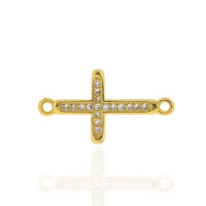 May include: Gold-toned cross charm with clear cubic zirconia stones. The cross has two jump rings for attaching to a necklace or bracelet.