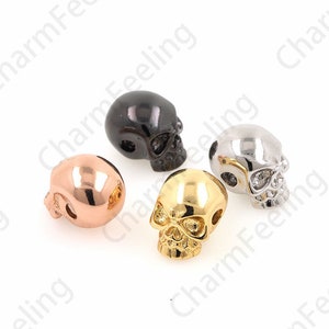 May include: Four skull-shaped beads in different metal finishes: gold, silver, rose gold, and black.