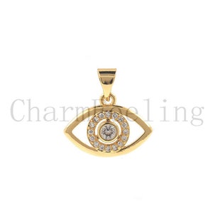 May include: Gold evil eye pendant with clear cubic zirconia stones. The pendant is in the shape of an eye with a circle of stones around the pupil.