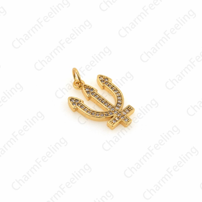 May include: Gold-toned trident charm with clear rhinestones. The trident is a three-pronged spear.